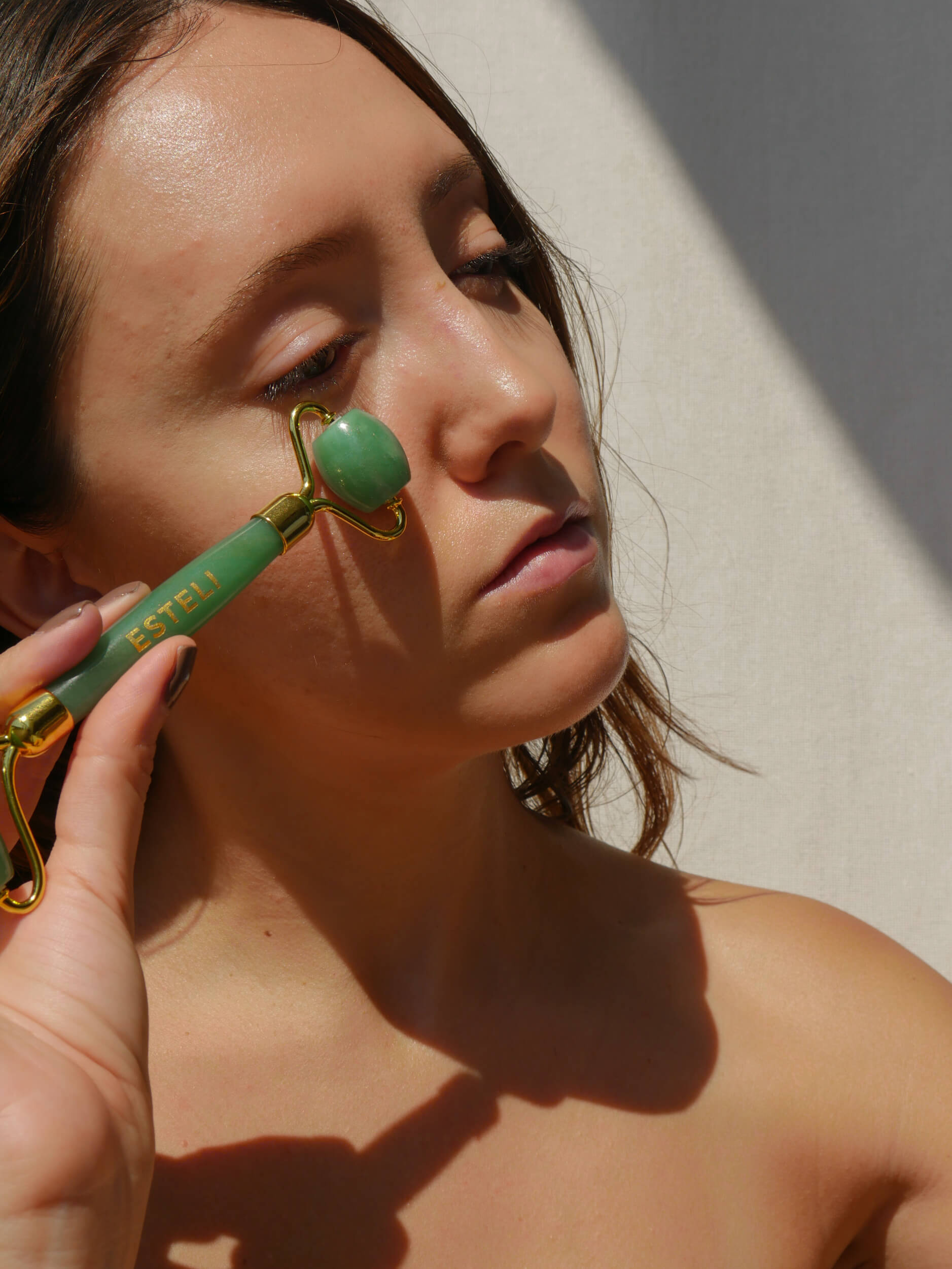Woman using Esteli Green Aventurine Facial Roller