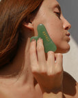 Woman using Estelí Green Aventurine Gua Sha with Oro Rosa Face Oil for radiant skin