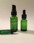 ESTELÍ Discovery Ritual featuring Rosa Jamaica Hydrating Face Mist, Oro Rosa Supercriticals Face Oil, and Verano Body Oil arranged on a warm cream background.