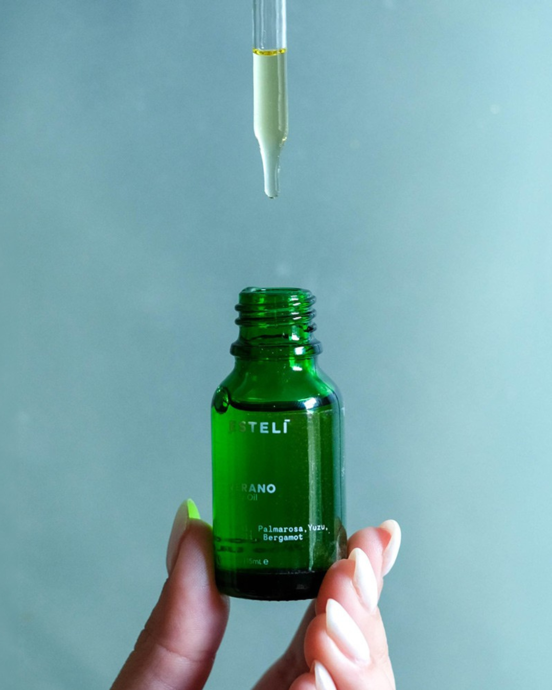 Dropper dispensing botanical body oil above ESTELÍ Verano Body Oil mini