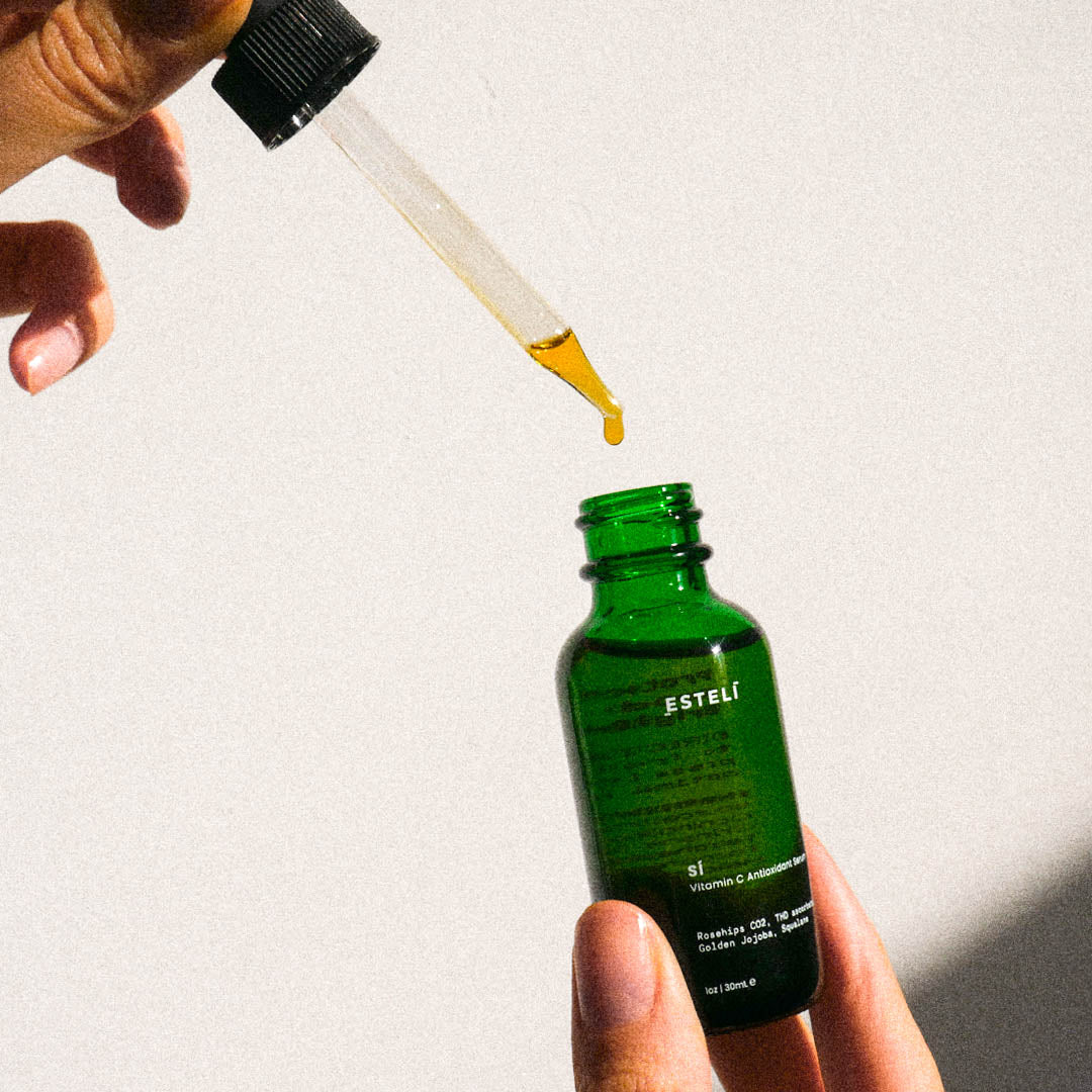 SÍ Vitamin C Serum golden oil dropper and green glass bottle in sunlight