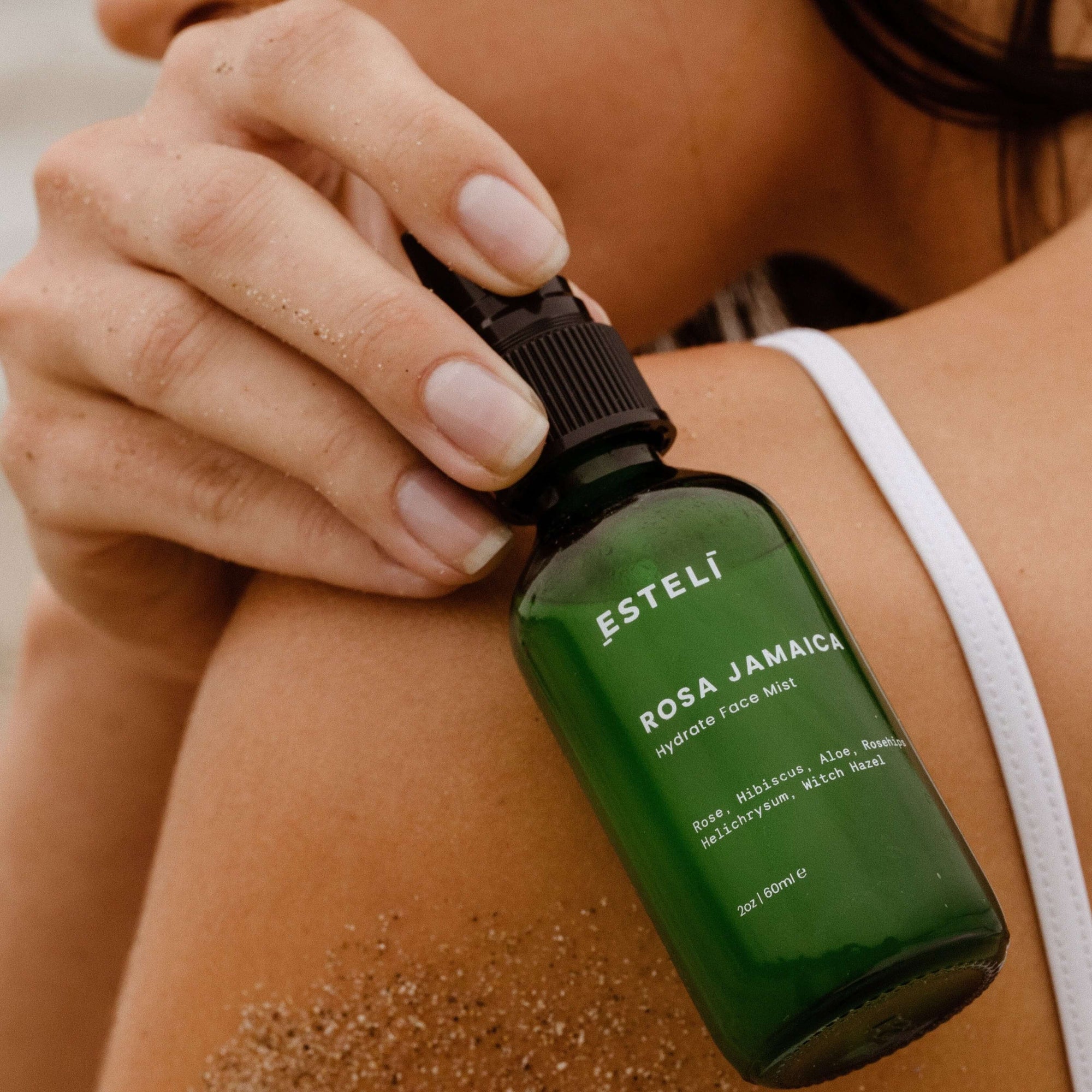 ESTELÍ Rosa Jamaica Hydrating Face Mist held near sun-warmed skin